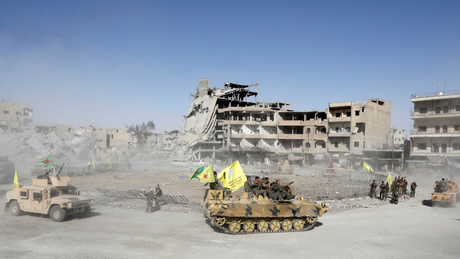 ‪مسلحون من قوات سوريا الديمقراطية بإحدى أهم ساحات مدينة الرقة وبدت حولها آثار دمار واسع‬ (رويترز)