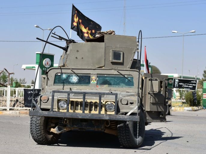 A picture taken on October 20, 2017 shows a humvee carrying fighters loyal to the federal goverment flying a flag bearing the words 'For thee, Hussein' oarked across a road in the region of Altun Kupri, about 50 kilometres (30 miles) from Arbil, the capital of autonomous Iraqi Kurdistan.Iraqi forces clashed with Kurdish peshmerga fighters on October 20 and retook control of the last sector of the disputed province of Kirkuk, with a general killed in the fighting, secu