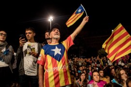BARCELONA, SPAIN - OCTOBER 01: People hold Catalan flags as they listen to Catalan President Carles Puigdemont speak via a televised press conference as they await the result of the Indepenence Referendum at the Placa de Catalunya on October 1, 2017 in Barcelona, Spain. More than five million eligible Catalan voters are estimated to visit 2,315 polling stations today for Catalonia's referendum on independence from Spain. The Spanish government in Madrid has declared