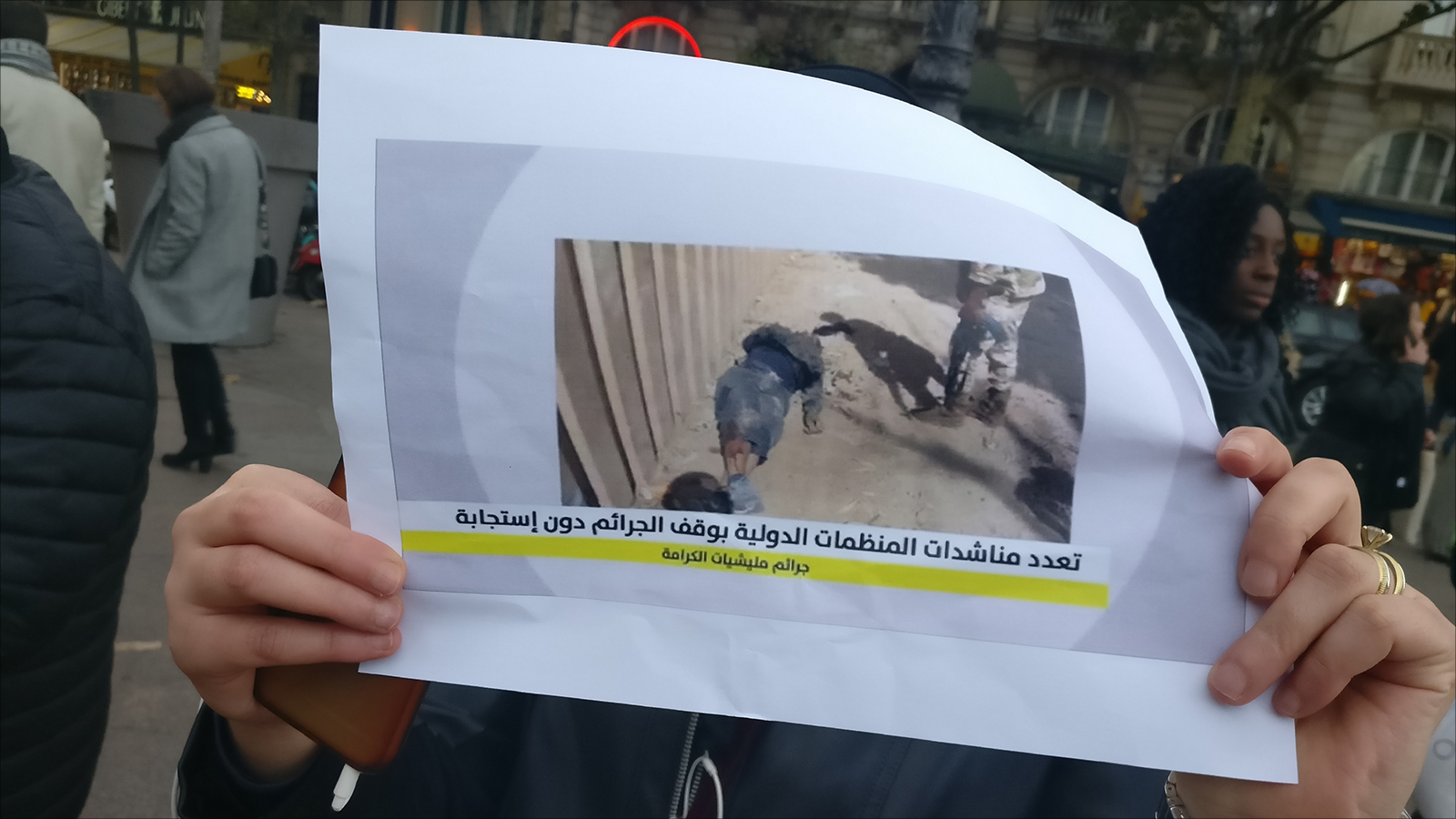 ناشطة تحمل صورة لعمليات إعدامات ميدانية نفذتها قوات حفتر في درنة ووثقتها المنظمات الحقوقية الدولية(الجزيرة)