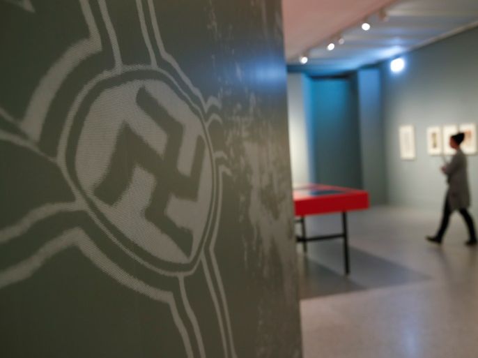 A woman walks past a Swastika during a media preview of the