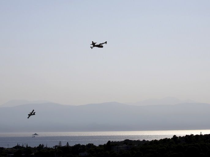 Firefighting planes maneuver during an operation to extinguish a forest fire over Costa village in the Argolida region, in Southeastern Greece July 20, 2015. Dozens of people were evacuated as firefighters fought the fire, which broke out on Monday afternoon in Panorama in Costa village at a forested area where dozens of summer houses are located, according to local media. REUTERS/Yannis Behrakis