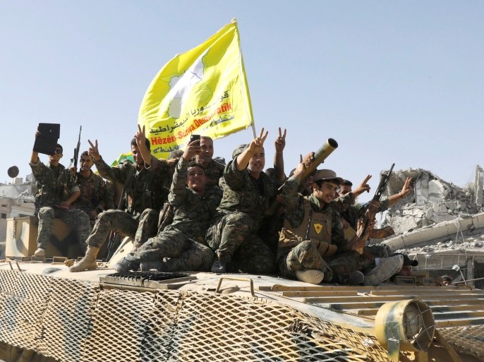 Syrian Democratic Forces (SDF) fighters ride atop of military vehicle as they celebrate victory in Raqqa, Syria, October 17, 2017. REUTERS/Erik De Castro
