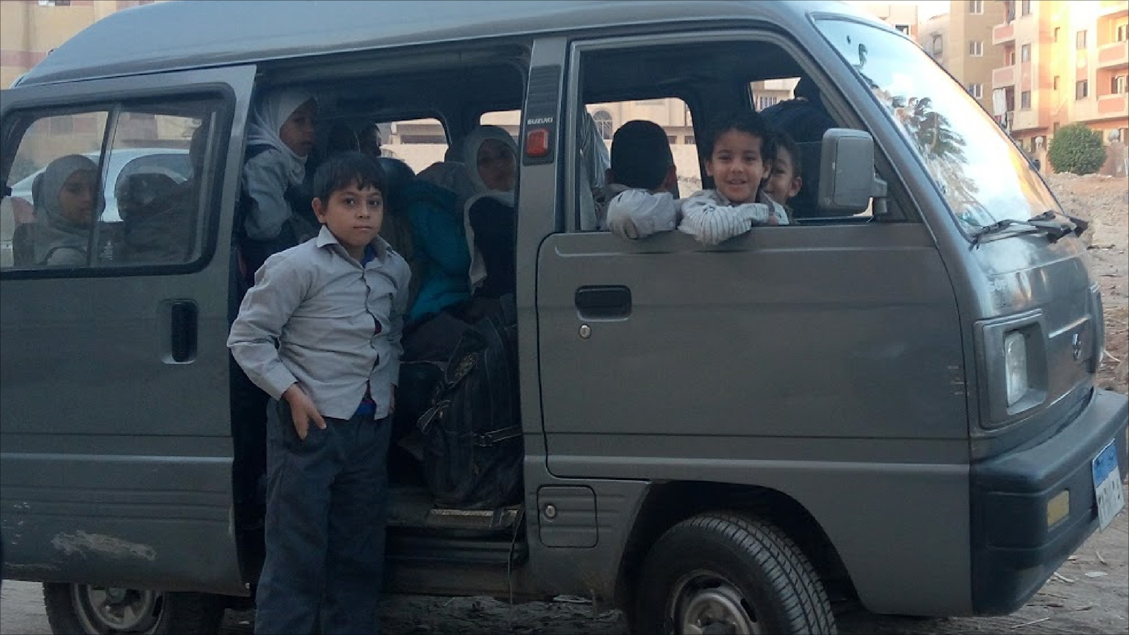 ‪كريم وزملاؤه يتكدسون في حافلة صغيرة تنقلهم للمدرسة‬ (الجزيرة)