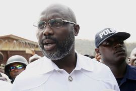 epa06405955 Liberian presidential candidate for the Coalition for Democratic Change (CDC), George Weah (C) leaves a polling station after casting his ballot in presidential elections run-off in Monrovia, Liberia, 26 December 2017.