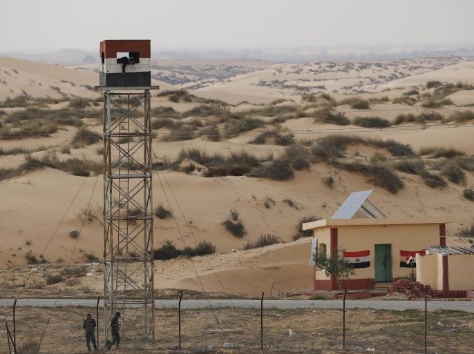An Egyptian policeman gestures from an observation tower is seen from the Israeli side of the border with Egypt's Sinai peninsula, in Israel's Negev Desert February 10, 2016. REUTERS/Amir Cohen