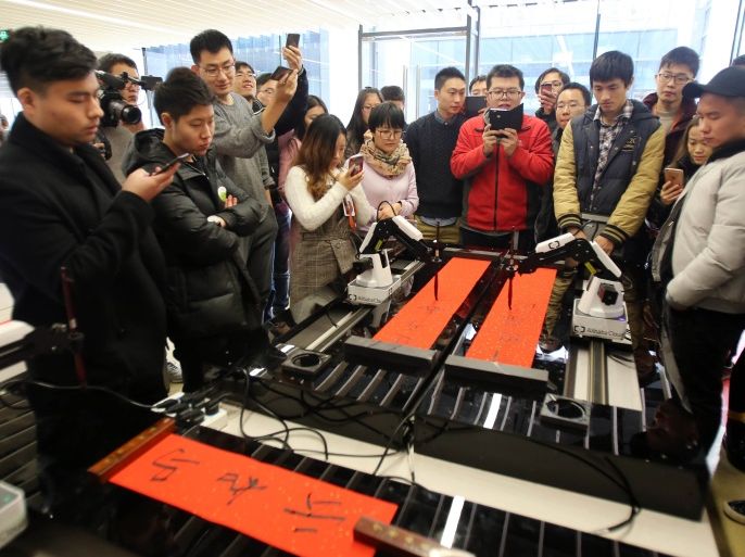 HANGZHOU, CHINA - JANUARY 16: Alibaba employees watch an artificial intelligence robot named ET writing Spring Festival couplets at Alibaba's Xixi District on January 16, 2017 in Hangzhou, Zhejiang Province of China. The robot named ET writes exclusive Spring Festival couplets for each Alibaba employee after using face recognition technology and speech recognition technology. (Photo by VCG/VCG via Getty Images)