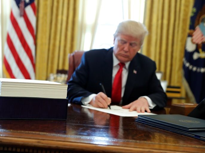 U.S. President Donald Trump signs sweeping tax overhaul legislation into law in the Oval Office at the White House in Washington, U.S. December 22, 2017. REUTERS/Jonathan Ernst