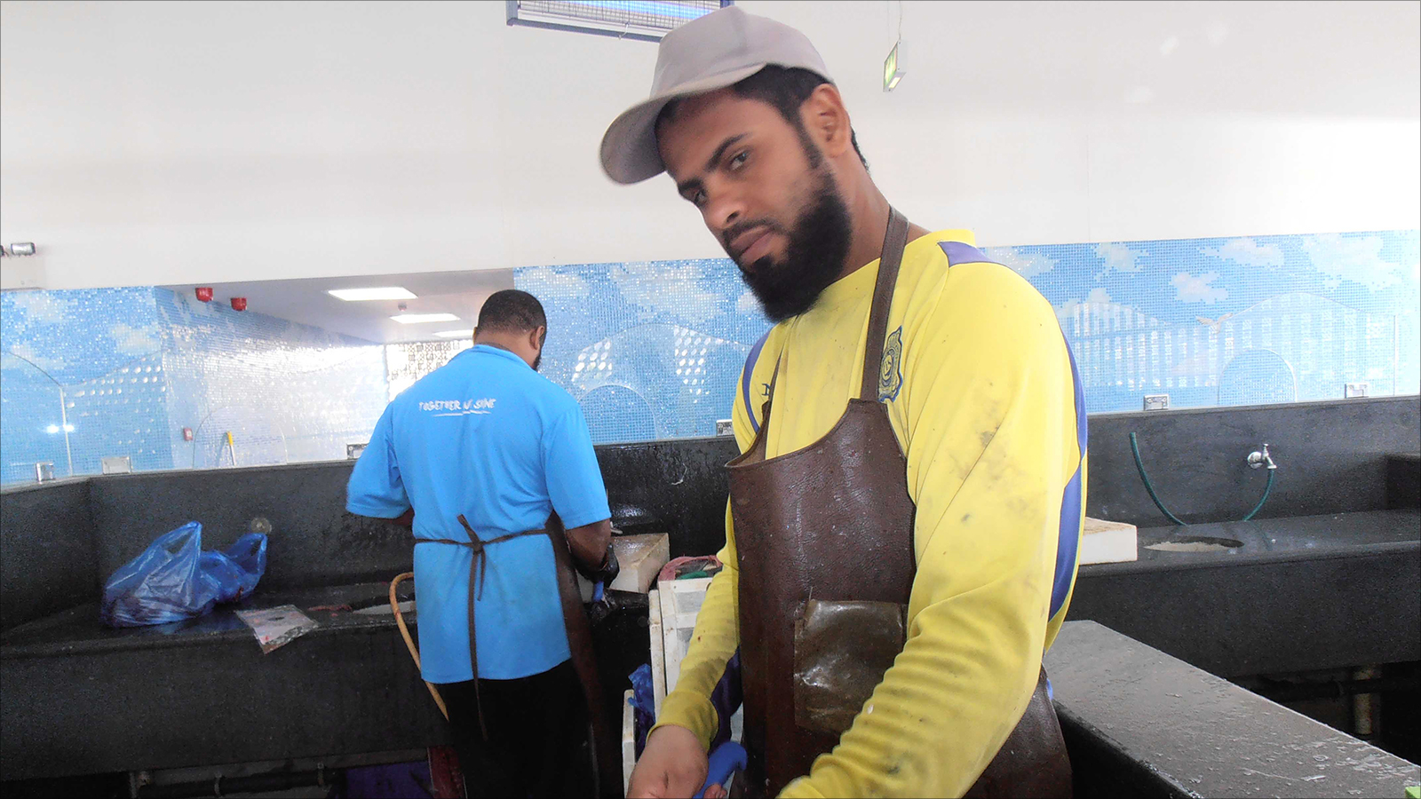 ‪ابن مبارك الرميمي شاب يعمل في تقطيع وتنظيف الأسماك بمسقط‬ (الجزيرة)
