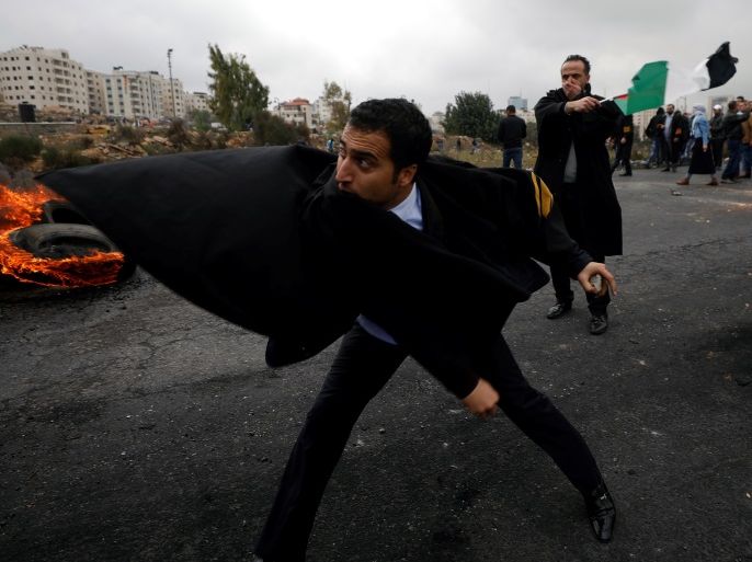 A Palestinian lawyer hurls stones towards Israeli troops during clashes at a protest against U.S. President Donald Trump's decision to recognise Jerusalem as the capital of Israel, near the Jewish settlement of Beit El, near the West Bank city of Ramallah December 13, 2017. REUTERS/Mohamad Torokman