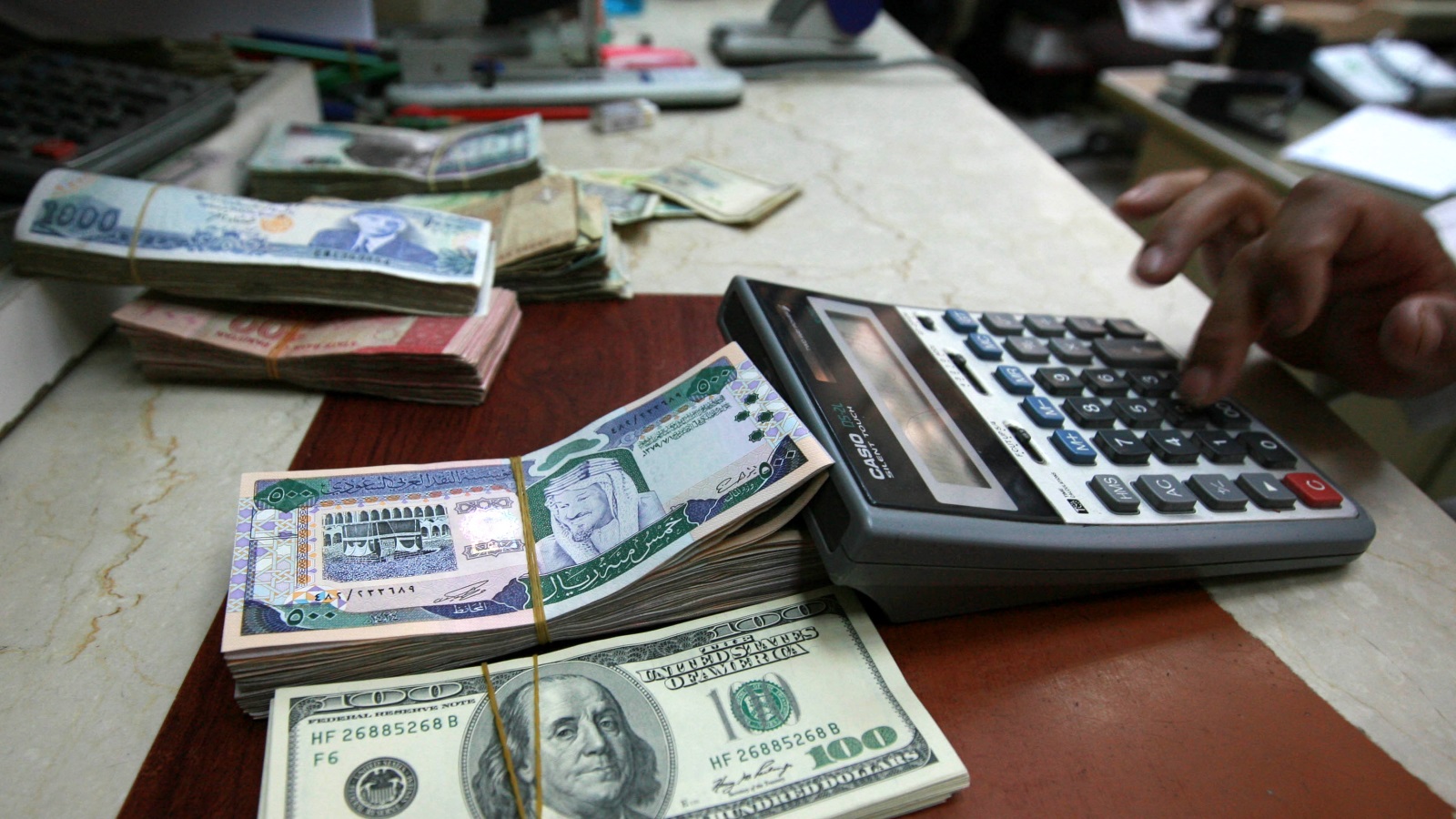 ‪أوراق نقدية من العملة السعودية أمام أوراق نقدية للدولار بمحل للصرافة‬  (رويترز)