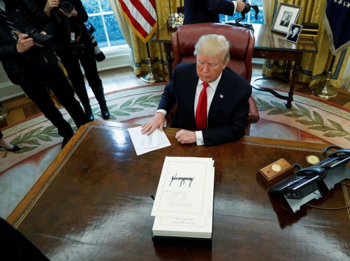 U.S. President Donald Trump sits at his desk as reporters exit after he signed sweeping tax overhaul legislation into law in the Oval Office at the White House in Washington, U.S. December 22, 2017. REUTERS/Jonathan Ernst