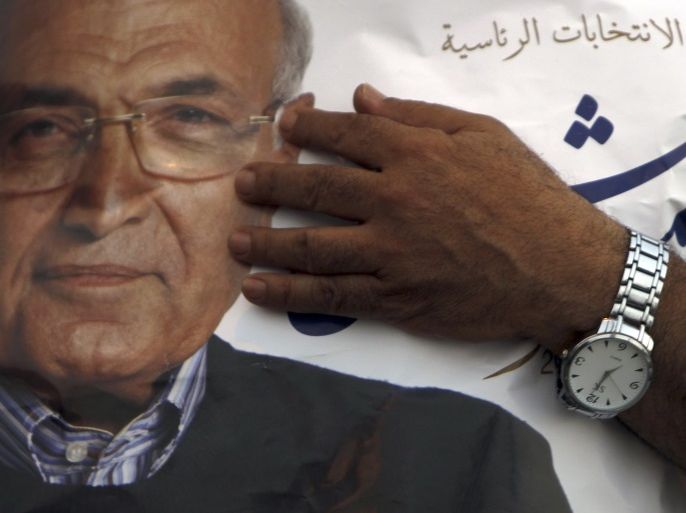 A supporter of former prime minister and current presidential candidate Ahmed Shafik holds a poster in protest against the Muslim Brotherhood's presidential candidate Mohamed Morsy during a rally in support of the Supreme Council for the Armed Forces (SCAF) in front of the military parade stand at Nasr City in Cairo June 23, 2012. Egyptians find out on Sunday whether their next president will be a former military officer or an Islamist from the army's old adversary, t