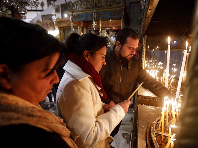epa06404715 Christian worshiper lights candles at the Church of the Nativity, built atop the site where Christians believe Jesus Christ was born, on Christmas Eve,in the West Bank city of Bethlehem, 24 December 2017. The Church of the Nativity, built on the site where Jesus Christ is believed to have been born in the West Bank city of Bethlehem, is administered jointly by Greek Orthodox, Roman Catholic, Armenian Apostolic and Syriac orthodox church. EPA-EFE/ABED AL HASHLAMOUN