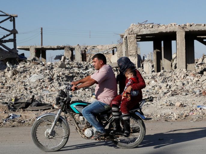 Motorists ride a motorcycle past ruins of buildings destroyed during fightings with the Islamic State militants in Kobani, Syria October 11, 2017. Picture taken October 11, 2017. REUTERS/Erik De Castro