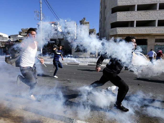 epa06378341 Palestinians run for cover from tear gas grenades fired by Israeli troops during clashes in the West Bank city of Bethlehem, 09 December 2017.