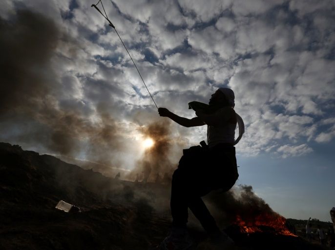 A Palestinian protester uses a sling to hurl stones towards Israeli troops during clashes as Palestinians call for a