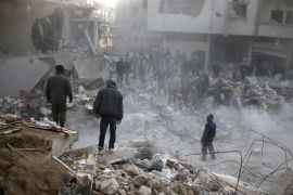 People stand on rubble of damaged buildings, after an airstrike in the besieged town of Hamoria, Eastern Ghouta, in Damascus, Syria Janauary 9, 2018. REUTERS/Bassam Khabieh
