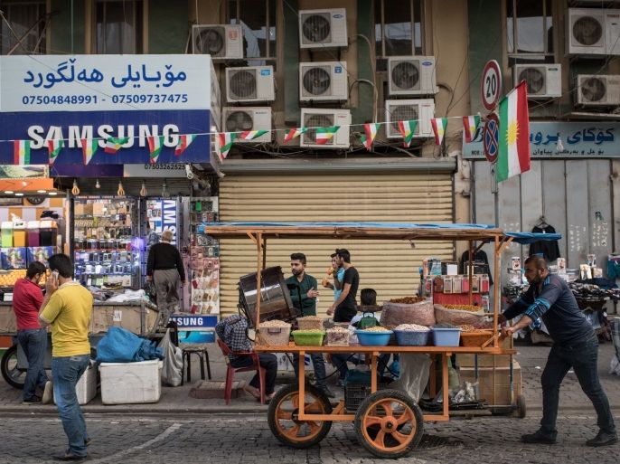 ERBIL, IRAQ - OCTOBER 27: A man pushes a cart past a Kurdish flag at a market in the old city on October 27, 2017 in Erbil, Iraq. After the Kurdish Regional Government held an independence referendum on September 25, 2017 the autonomous Kurdish region of northern Iraq has gone through political upheaval after Baghdad took measures against the independence movement shutting down the regions airports to international flights and taking over the disputed city of Kirkuk. Ku