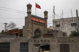 KASHGAR, CHINA - JUNE 28: A Chinese flag flies over a local mosque recently closed by authorities as an ethnic Uyghur woman sells bread at her bakery on June 28, 2017 in the old town of Kashgar, in the far western Xinjiang province, China. Kashgar has long been considered the cultural heart of Xinjiang for the province's nearly 10 million Muslim Uyghurs. At an historic crossroads linking China to Asia, the Middle East, and Europe, the city has changed under Chinese rule with government development, unofficial Han Chinese settlement to the western province, and restrictions imposed by the Communist Party. Beijing says it regards Kashgar's development as an improvement to the local economy, but many Uyghurs consider it a threat that is eroding their language, traditions, and cultural identity. The friction has fuelled a separatist movement that has sometimes turned violent, triggering a crackdown on what China's government considers 'terrorist acts' by religious extremists. Tension has increased with stepped up security in the city and the enforcement of measures including restrictions at mosques. (Photo by Kevin Frayer/Getty Images)