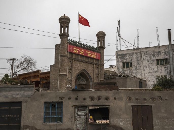 KASHGAR, CHINA - JUNE 28: A Chinese flag flies over a local mosque recently closed by authorities as an ethnic Uyghur woman sells bread at her bakery on June 28, 2017 in the old town of Kashgar, in the far western Xinjiang province, China. Kashgar has long been considered the cultural heart of Xinjiang for the province's nearly 10 million Muslim Uyghurs. At an historic crossroads linking China to Asia, the Middle East, and Europe, the city has changed under Chinese rule with government development, unofficial Han Chinese settlement to the western province, and restrictions imposed by the Communist Party. Beijing says it regards Kashgar's development as an improvement to the local economy, but many Uyghurs consider it a threat that is eroding their language, traditions, and cultural identity. The friction has fuelled a separatist movement that has sometimes turned violent, triggering a crackdown on what China's government considers 'terrorist acts' by religious extremists. Tension has increased with stepped up security in the city and the enforcement of measures including restrictions at mosques. (Photo by Kevin Frayer/Getty Images)
