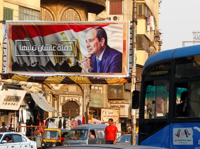 People walk near a poster of Egyptian President Abdel Fattah al-Sisi of the campaign titled, “Alashan Tabneeha” (So You Can Build It), that demands al-Sisi to run in the next year's presidential election, at Sayeda Zainab square in downtown of Cairo, Egypt October 17, 2017. Picture taken October 17, 2017. REUTERS/Amr Abdallah Dalsh