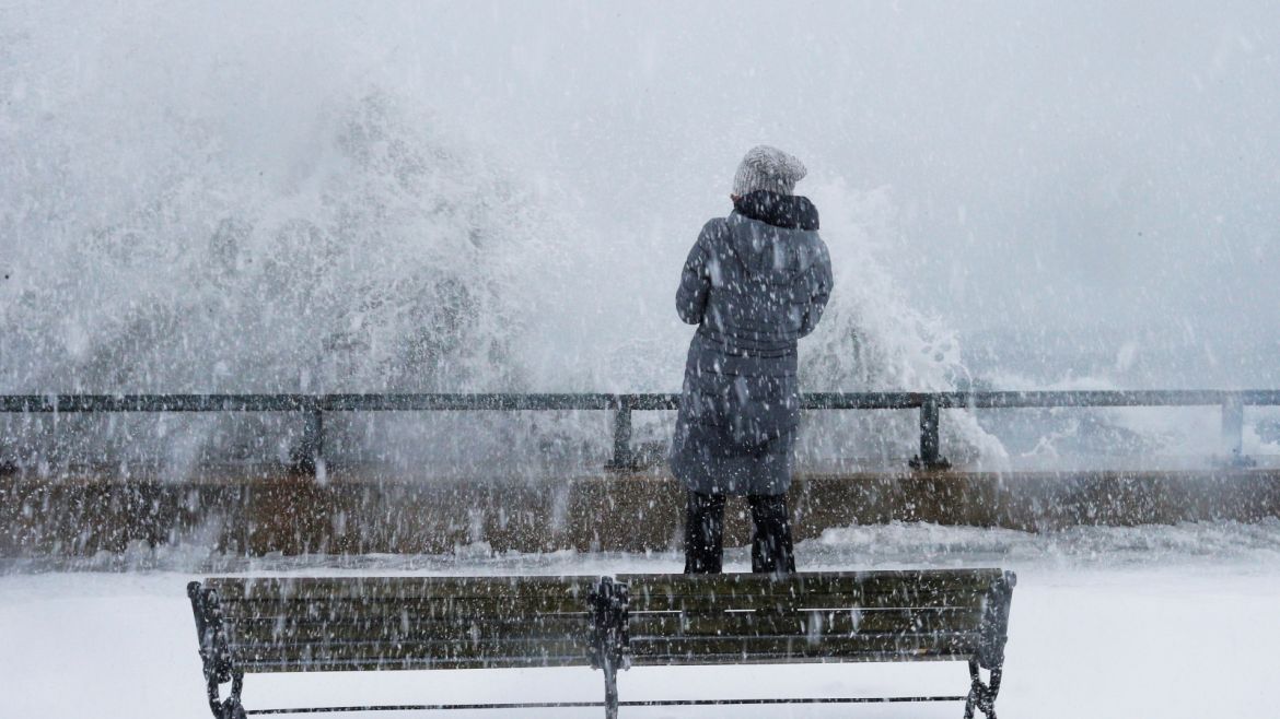 A woman watches as ocean waves overtop the seawall during a winter snow storm in the Boston suburb of Lynn, Massachusetts, U.S., January 4, 2018. REUTERS/Brian Snyder
