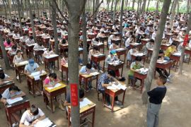 Students take term final exam among trees outside a classroom building at a middle school in Xinxiang, Henan province, China, July 3, 2015. The school set up the exam outdoor to create a more comfortable environment for the students, according to local media. Picture taken July 3, 2015. REUTERS/Stringer CHINA OUT. NO COMMERCIAL OR EDITORIAL SALES IN CHINA.