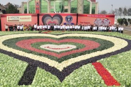 Participants stand behind a mosaic made up of vegetables at Ludhiana, in the northern Indian state of Punjab February 21, 2014. More than a thousand participants, including doctors and Ranbaxy Laboratories Ltd employees, created the heart-shaped mosaic measuring 480 square metres (5,167 square ft.) to set a new Guinness World Records of the largest vegetable mosaic, beating the existing record set by Japan. The seven-layered mosaic promoting healthy eating for the heart was made using about 19,825 kg (43,706 lbs) of vegetables, a media release said. REUTERS/Stringer (INDIA - Tags: FOOD SOCIETY)