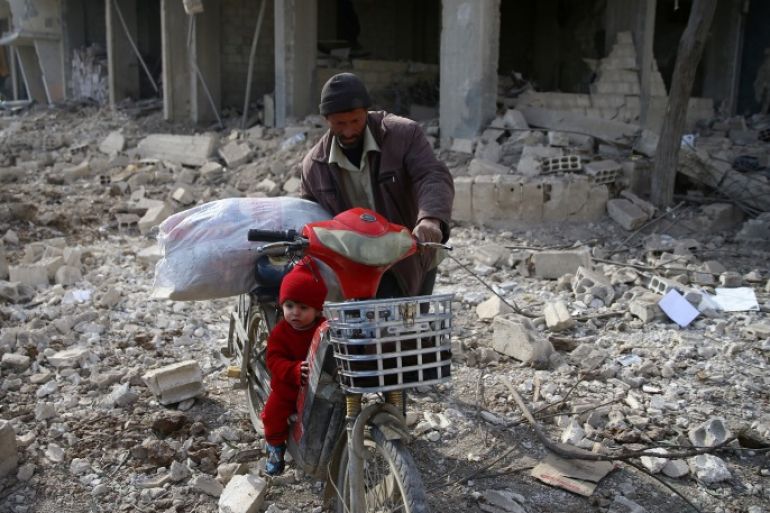 A man is seen with a child who rides a bicycle inside damaged area in Misraba, Eastern Ghouta, near Damascus, Syria January 11, 2018. REUTERS/Bassam Khabieh
