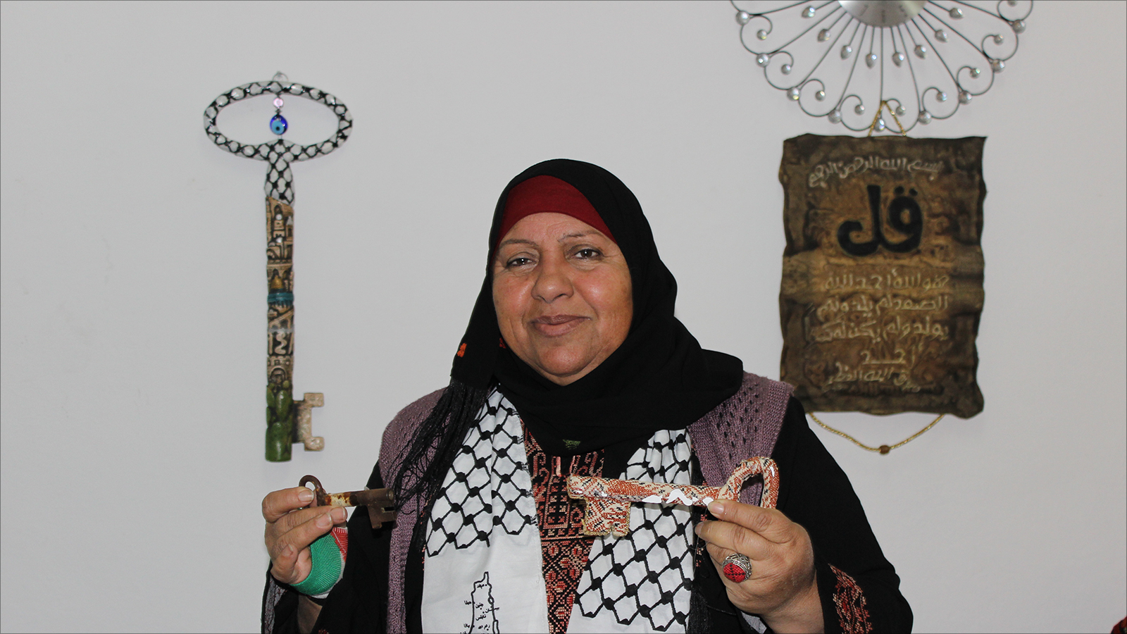 فاطمة تحمل مفتاح منزل عائلتها في قرية بئر ماعين ومفتاح منزل آخر (الجزيرة)