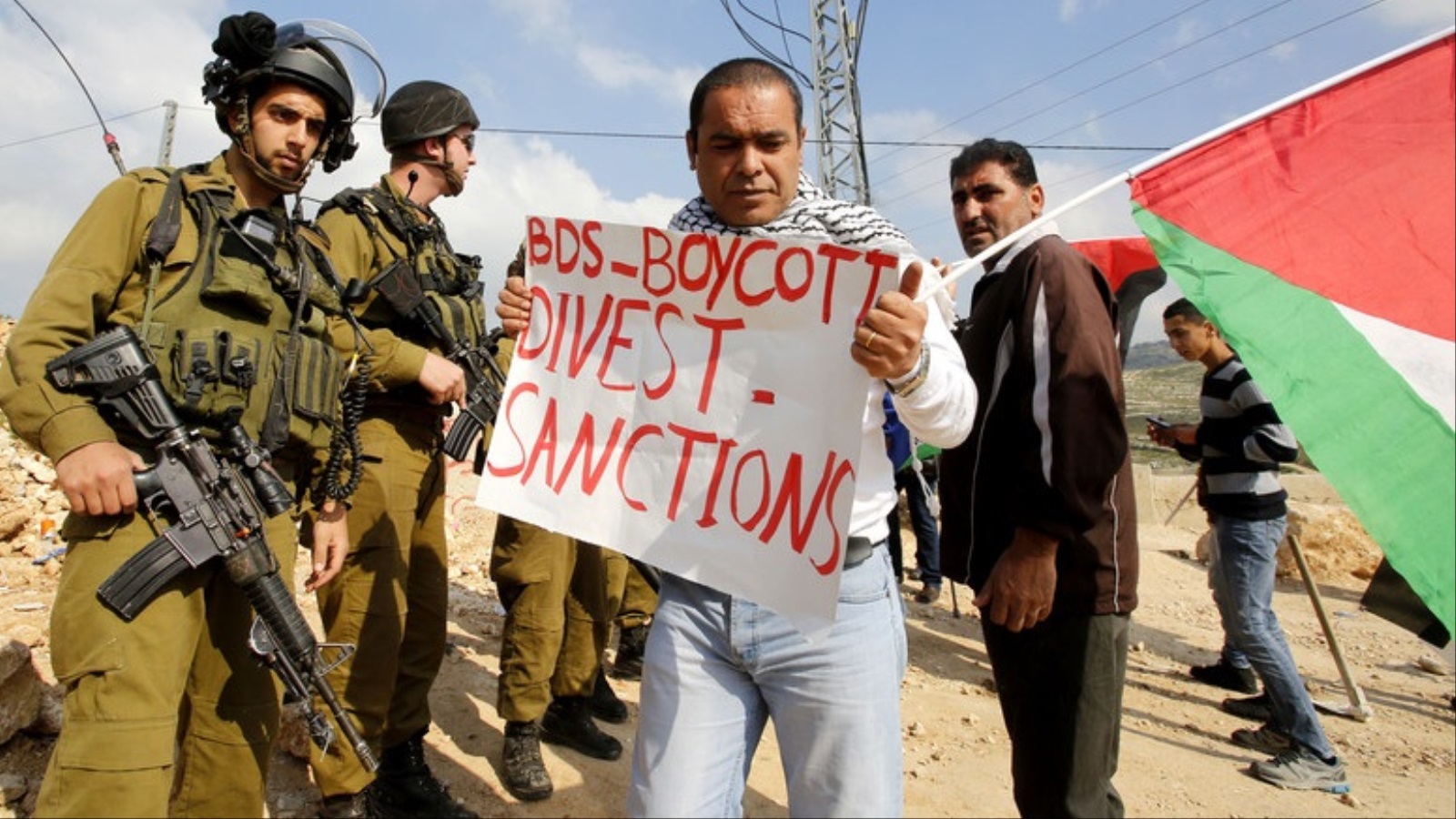 ‪فلسطيني يحمل لافتة تشير إلى حركة المقاطعة العالمية (‬ (الأوروبية)