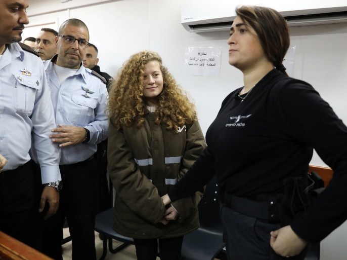 Palestinian teen Ahed Tamimi enters a military courtroom escorted by Israeli security personnel at Ofer Prison, near the West Bank city of Ramallah, January 15, 2018. REUTERS/Ammar Awad