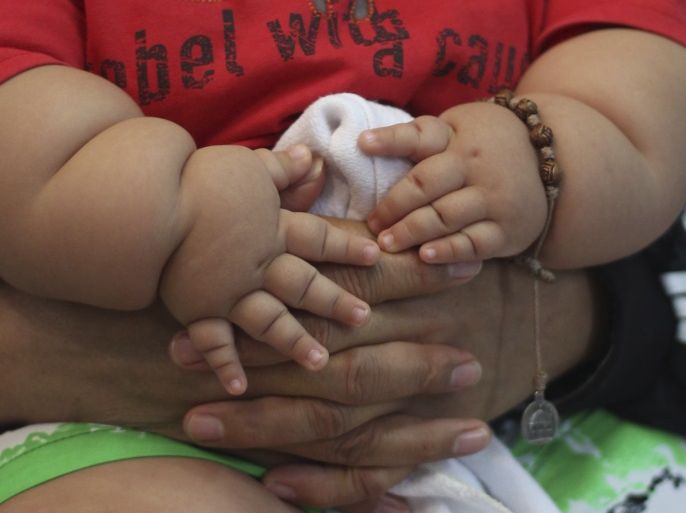 Eight-month-old Santiago Mendoza is held on to by his mother Eunice Fandino as they wait at a clinic for the obese in Bogota March 19 ,2014. Mendoza, who weighs 20 kg, will be put on a diet, therapist Salvador Palacios said. REUTERS/John Vizcaino (COLOMBIA - Tags: SOCIETY HEALTH)