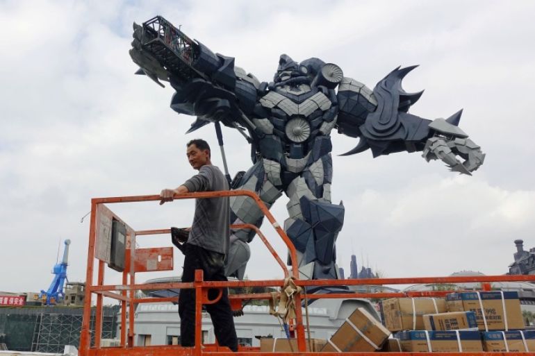 A worker rides on a cart in front of a giant robot statue at the Oriental Science Fiction Valley theme park in Guiyang, Guizhou province, China November 16, 2017. Picture taken November 16, 2017. REUTERS/Joseph Campbell