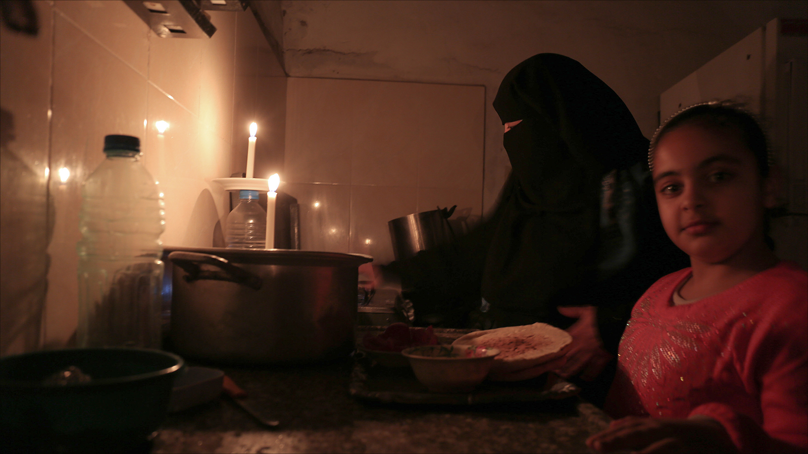 ‪أسرة أحمد المصري تحضر طعامها على ضوء الشموع‬ (الجزيرة)