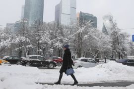A woman walks along a street after a heavy snowfall, with the Moscow International Business Center also known as