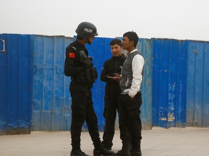 A police officer talks to men in a street in Kashgar, Xinjiang Uighur Autonomous Region, China, March 24, 2017. REUTERS/Thomas Peter