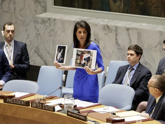 epa05890393 Nikki Haley, the United States' Ambassador to the United Nations, holds up pictures of victims of a chemical attack in Syria during an emergency meeting of the United Nations Security Council at United Nations headquarters in New York, New York, USA, 05 April 2017. Britain, France and the United States have called for a resolution condemning the attack, in which 72 people were reportedly killed, including 20 children, but Russia has said it does not support