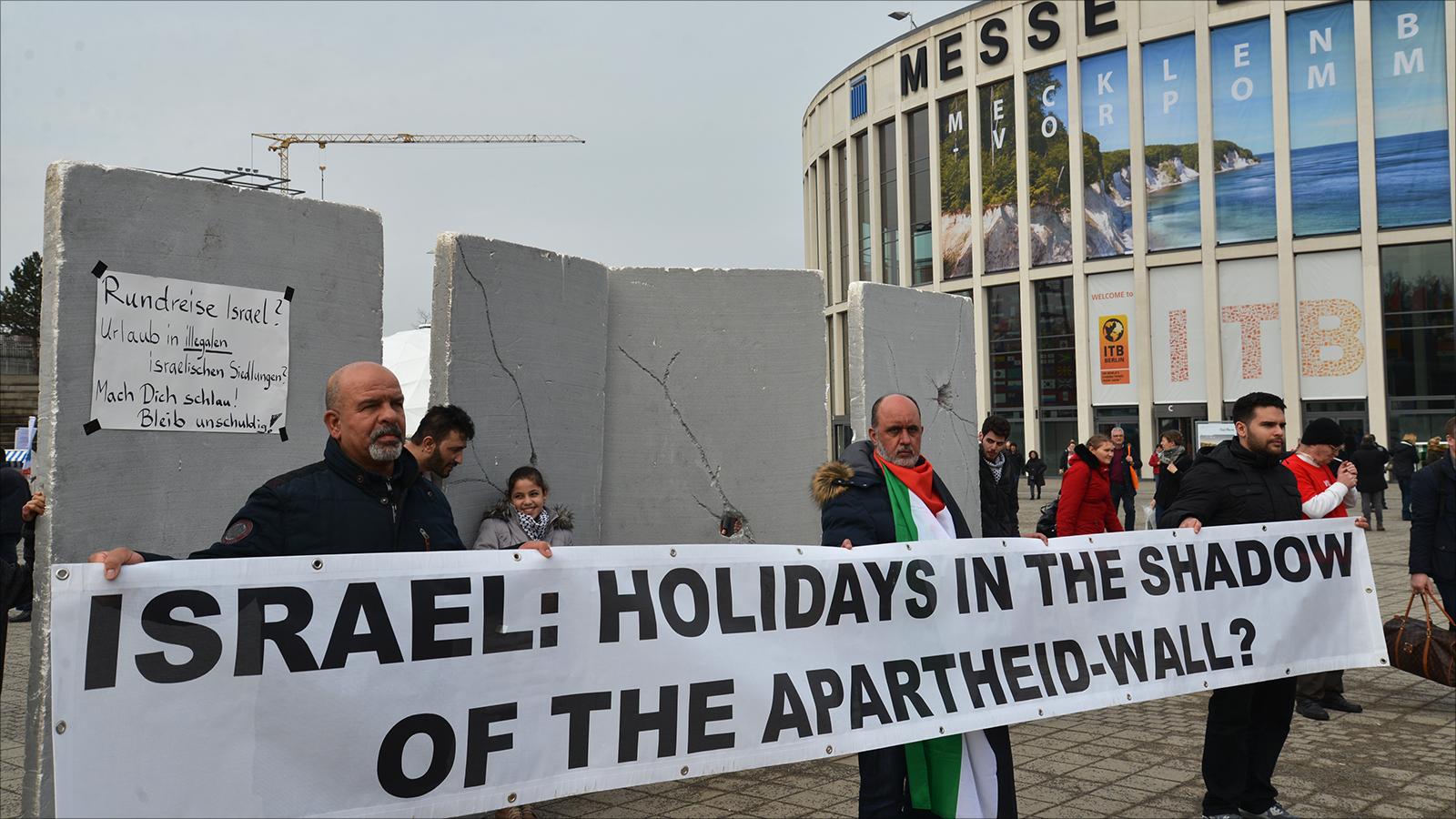 المشاركون في الوقفة وضعوا مجسما لجدار الفصل العنصري أمام بوابة بورصة برلين للفت أنظار الزائرين إلى معاناة الفلسطينيين (الجزيرة)