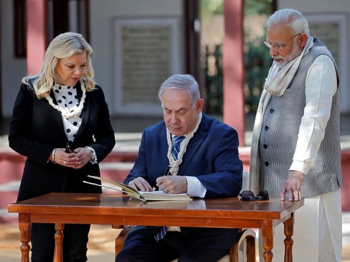 Israeli Prime Minister Benjamin Netanyahu writes a message in the visitor's book as his wife Sara and his Indian counterpart Narendra Modi look on during their visit to Gandhi Ashram in Ahmedabad, India, January 17, 2018. REUTERS/Amit Dave