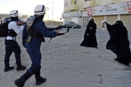 epa03975586 A riot policeman (L) points a gun at female protesters as they attempt to free an arrested young protester during clashes following the third day of the funeral for 15-year-old Ahmed Abdul-Ameer in Sanabis village, a suburb of the Bahraini capital Manama 03 December 2013.