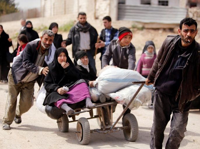 A man pulls a cart with a woman sitting on it as people flee the rebel-held town of Hammouriyeh, in the village of Beit Sawa, eastern Ghouta, Syria March 15, 2018. REUTERS/Omar Sanadiki
