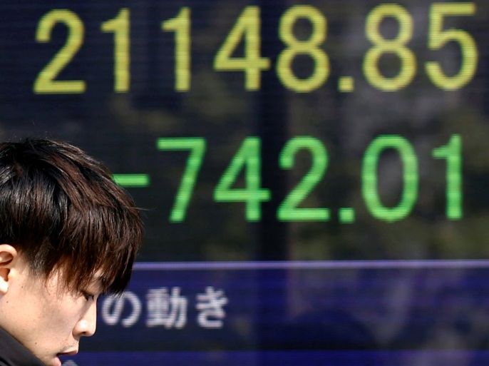 A man walks past an electronic board showing Japan's Nikkei average outside a brokerage in Tokyo, Japan, February 9, 2018. REUTERS/Toru Hanai