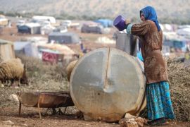 epa06434464 A displaced woman fills her container with water inside the Atamah camp, at the Syrian-Turkish broder in Idlib, Syria, 12 January 2018.