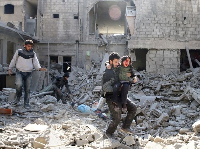 ATTENTION EDITORS - VISUAL COVERAGE OF SCENES OF INJURY OR DEATH A man carries an injured boy as he walks on rubble of damaged buildings in the rebel held besieged town of Hamouriyeh, eastern Ghouta, near Damascus, Syria, February 21, 2018. REUTERS/Bassam Khabieh TEMPLATE OUT