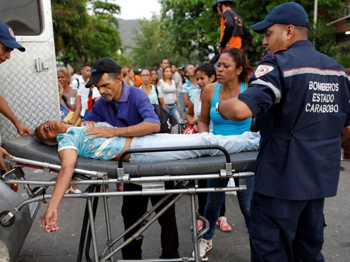Paramedics help a relative of inmates held at the General Command of the Carabobo Police, who fainted, outside the prison, where a fire occurred in the cells area, according to local media, in Valencia, Venezuela March 28, 2018. REUTERS/Carlos Garcia Rawlins