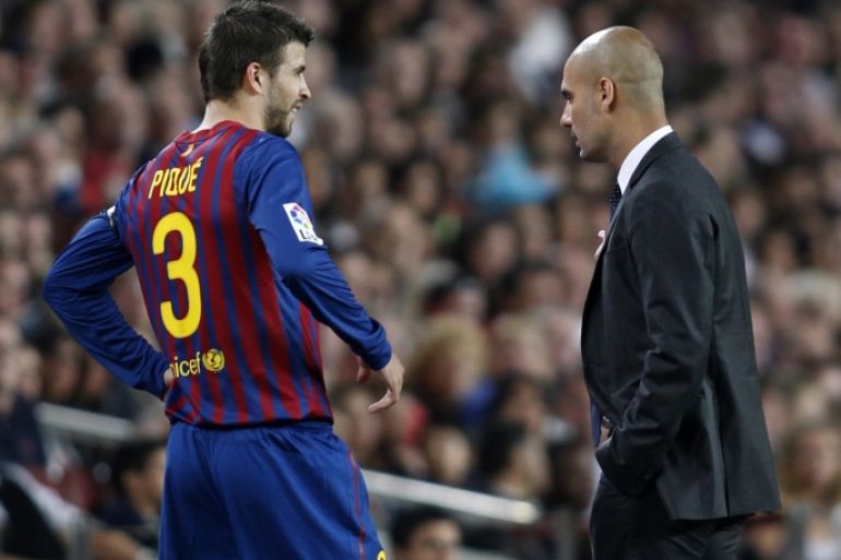 Barcelona's player Gerard Pique (L) talks with Barcelona's coach Pep Guardiola after leaving the pitch injured during their Spanish first division soccer match against Racing de Santander at Nou Camp stadium in Barcelona October 15, 2011. REUTERS/Gustau Nacarino (SPAIN - Tags: SPORT SOCCER)