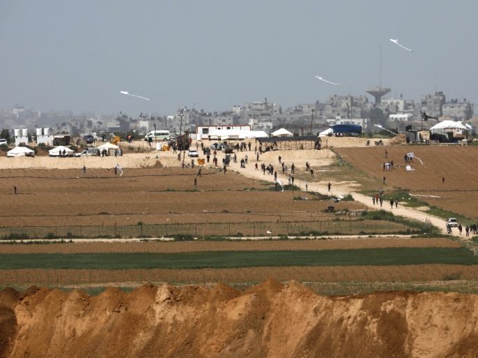Palestinians walk near a tent camp on the Gaza side of the Israel-Gaza Strip border, as seen from the Israeli side of the border, March 29, 2018. REUTERS/Amir Cohen