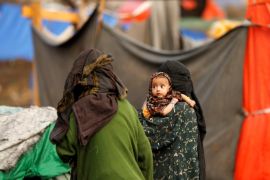 A woman carries a child near their tent at a camp for internally displaced people (IDPs) near Sanaa, Yemen March 17, 2018. Picture taken March 17, 2018. REUTERS/Khaled Abdullah